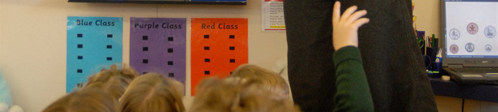 Children in a classroom with hands in the air