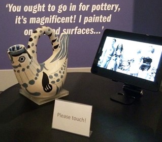 Museum display includes a 3D replica of a Picasso ceramic, designed to be held, in front of a glass case with the original. Digital screen shows the technologies used in production.