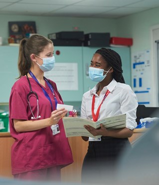 One female in scrubs showing medicine to a placement student