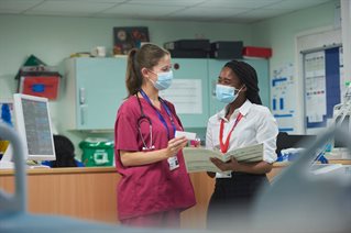 One female in scrubs showing medicine to a placement student