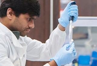 Scientist in a white lab coat testing samples in a lab