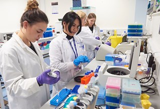 Three female students with female lecturer in ecology lab