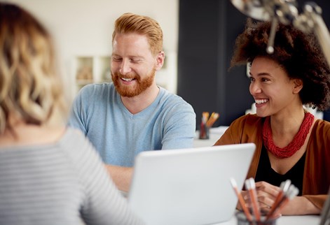three people laughing round a laptop